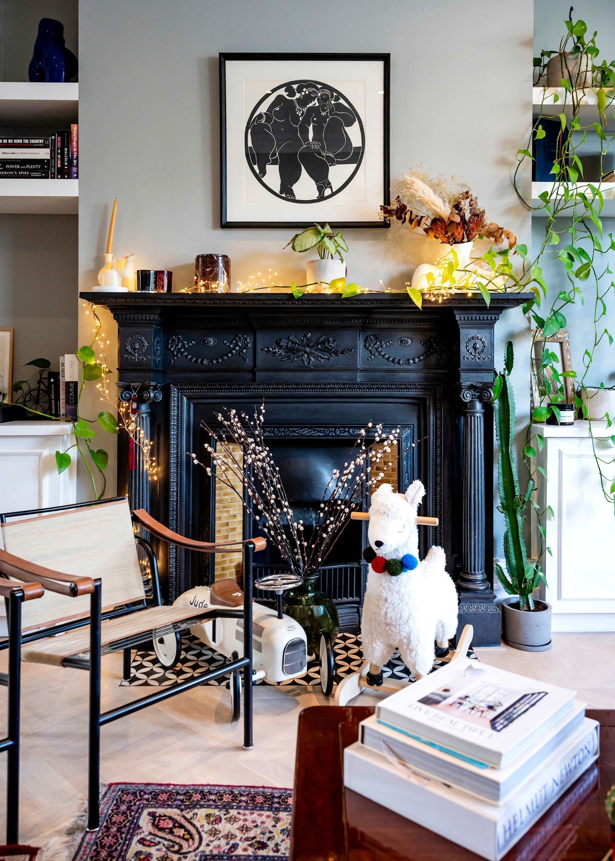A living room with a fireplace, a framed artwork, a plush toy, and a bookshelf.
