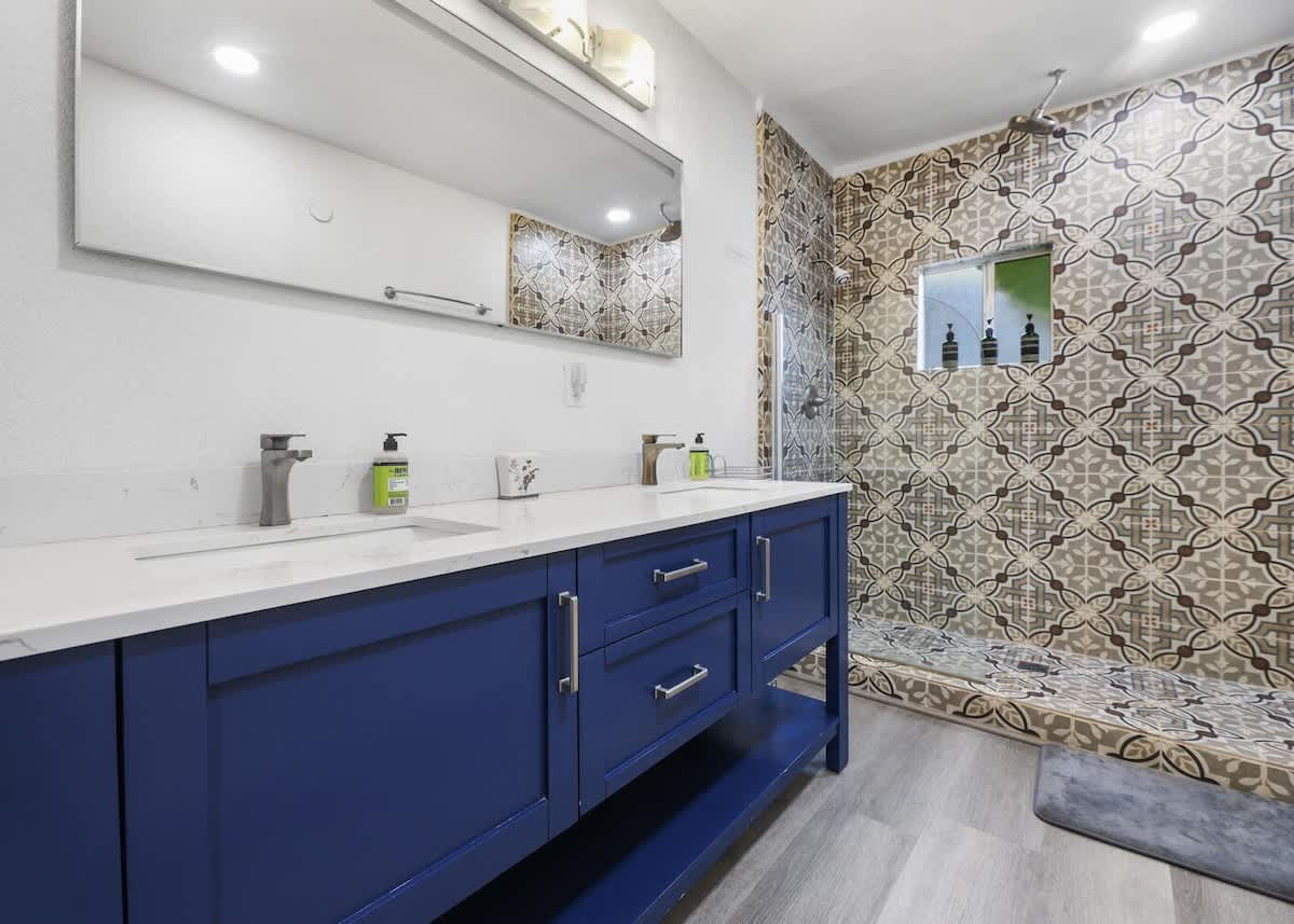 A bathroom with a white sink, blue cabinets, and patterned tiles on the walls.