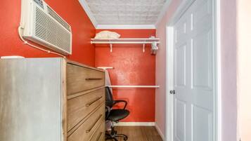 Una habitación pequeña con un aparador de madera, una silla de oficina negra, una puerta blanca y una pared roja.