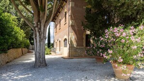 A gravel path leading to a brick building with arched windows and a stone wall.