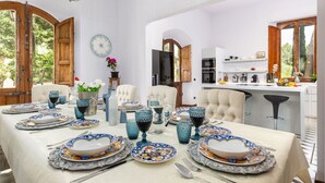 A dining area with a table set for six, featuring blue and white patterned plates and glasses.