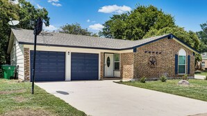 A two-story house with a brick exterior, a garage, and a front yard. - Family Home in Ft Worth Suburbs Near Benbrook Lake (Crowley)