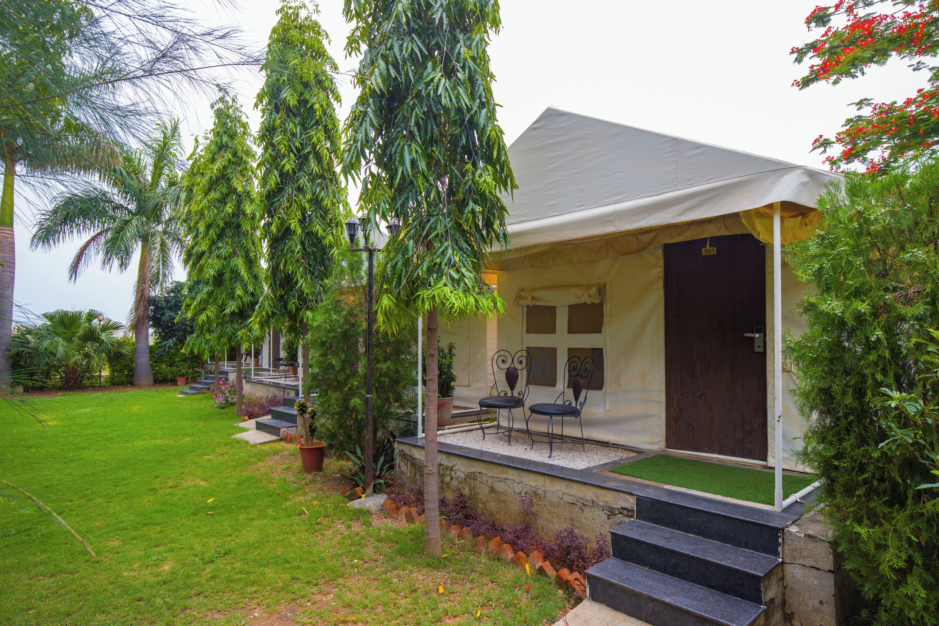 A bungalow with a porch, outdoor seating, and a door.