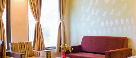 A room with a sofa, armchair, and a small table with a vase of flowers.