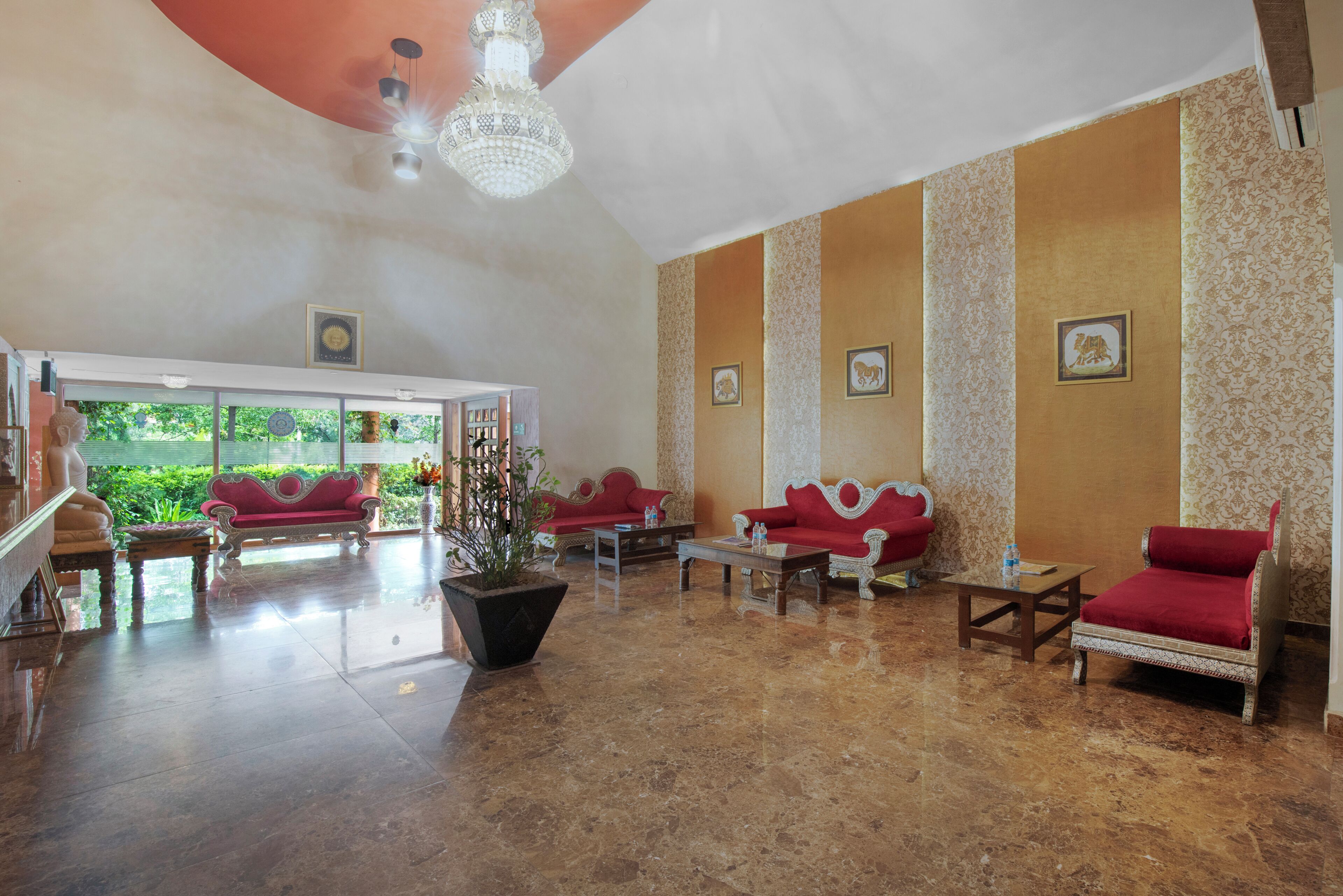A spacious lobby with red sofas, a chandelier, and framed artwork on the walls.