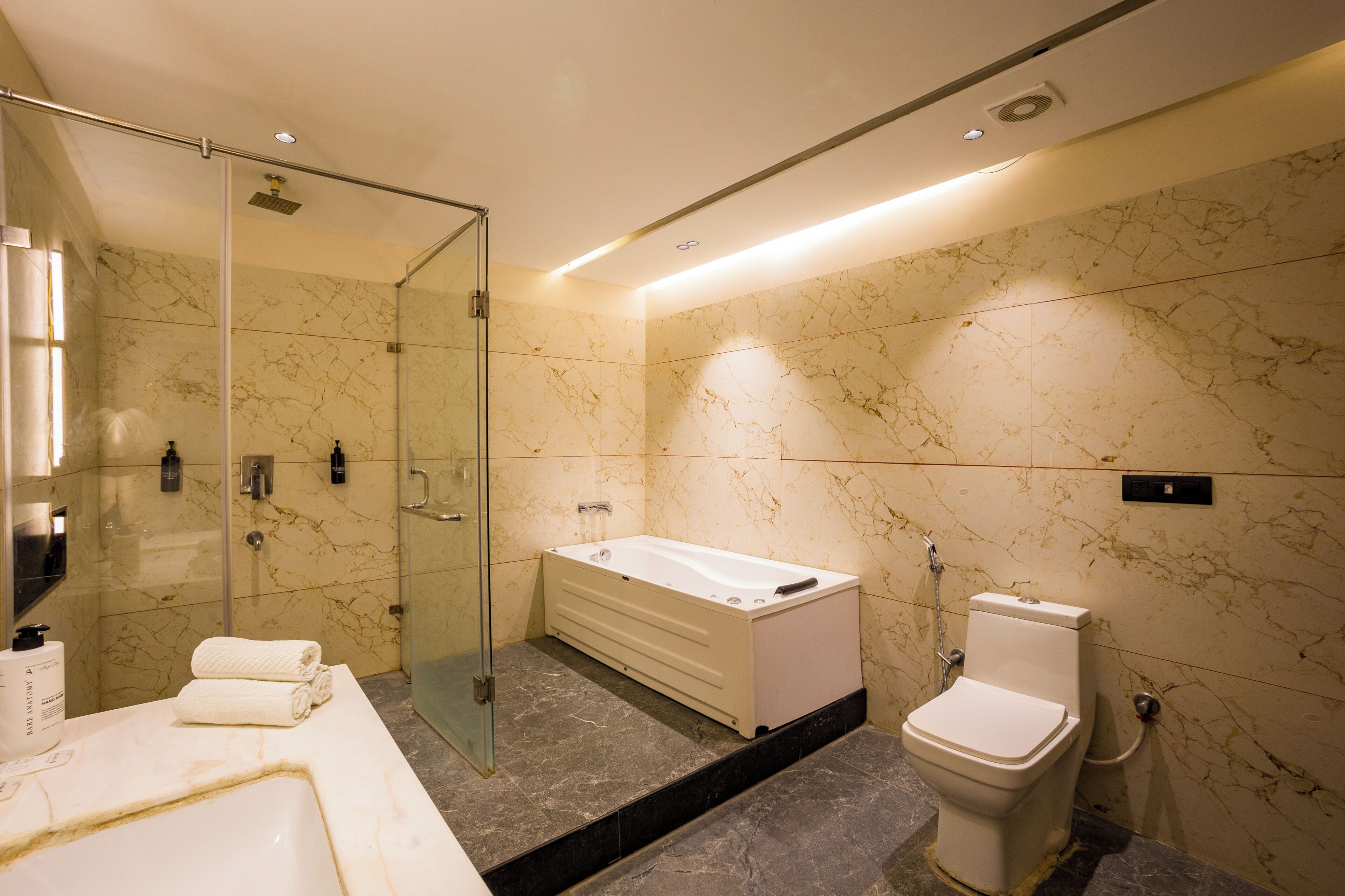 Un baño moderno con cabina de ducha de vidrio, bañera independiente y retrete.