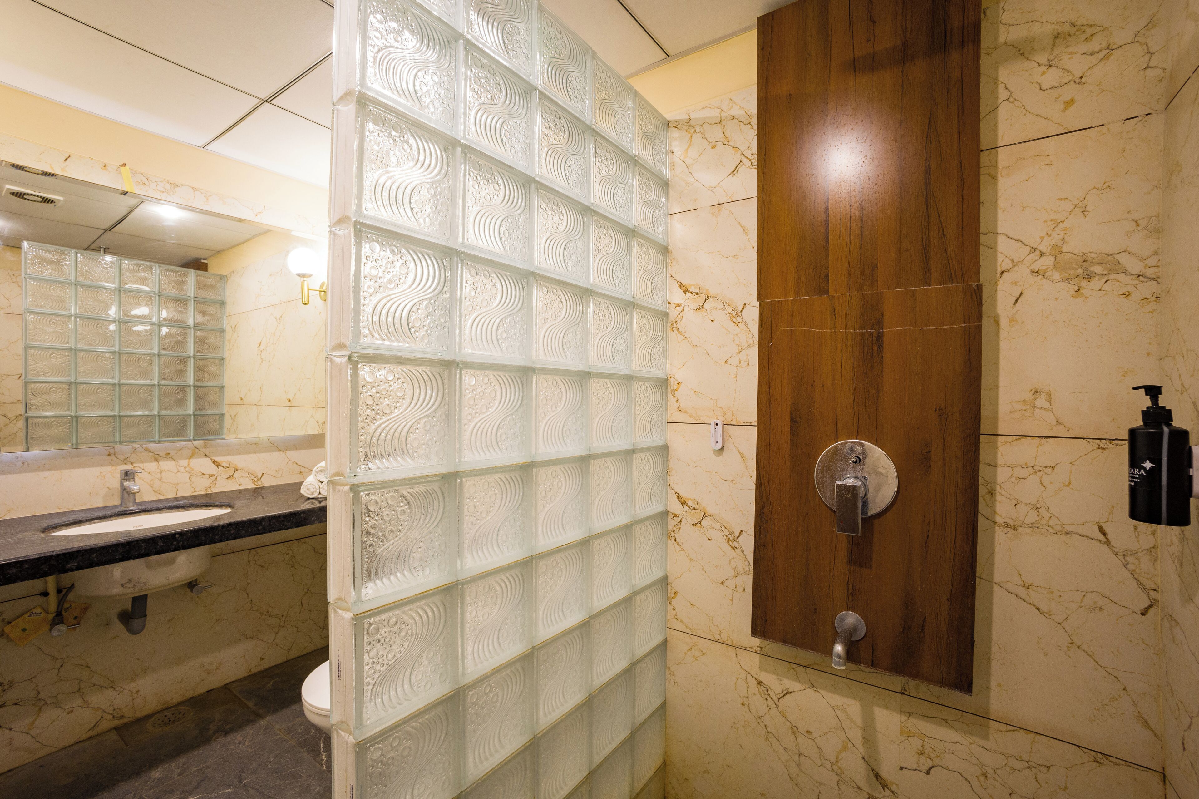 A bathroom with a marble sink, a glass partition, and a wooden door.