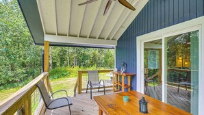 A wooden deck with a table and chairs, a ceiling fan, and a view of the surrounding greenery. - Lake Hamilton Retreat w/ Kayaks & Spacious Yard! (Hot Springs)
