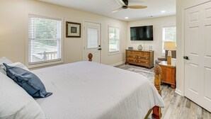 A bedroom with a large bed, a dresser, a television, and a ceiling fan. - Lake Hamilton Retreat w/ Kayaks & Spacious Yard! (Hot Springs)
