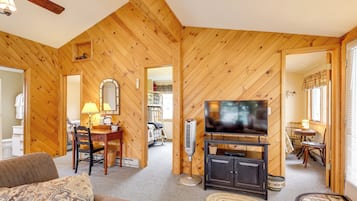 A wooden interior with a television, a dining table, and a sofa.