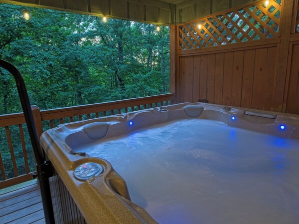 A hot tub on a wooden deck with a view of trees. - Cabin w/ Hot Tub · Fireplace · EV Charger (Asheville)
