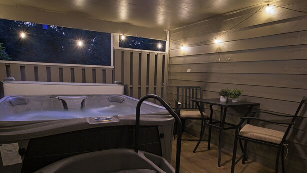 A hot tub with steps, a table with chairs, and a small plant on the table.