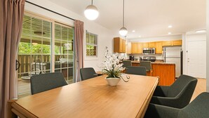 A modern kitchen with wooden cabinets, a stainless steel refrigerator, and a dining area with a wooden table and chairs. - Hot Tub · Fire Pit · EV Charger · Near Asheville (Asheville)