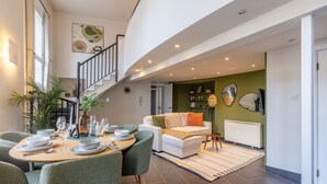Ein modernes Wohnzimmer mit Essbereich, einer Treppe und einer grünen Akzentwand.