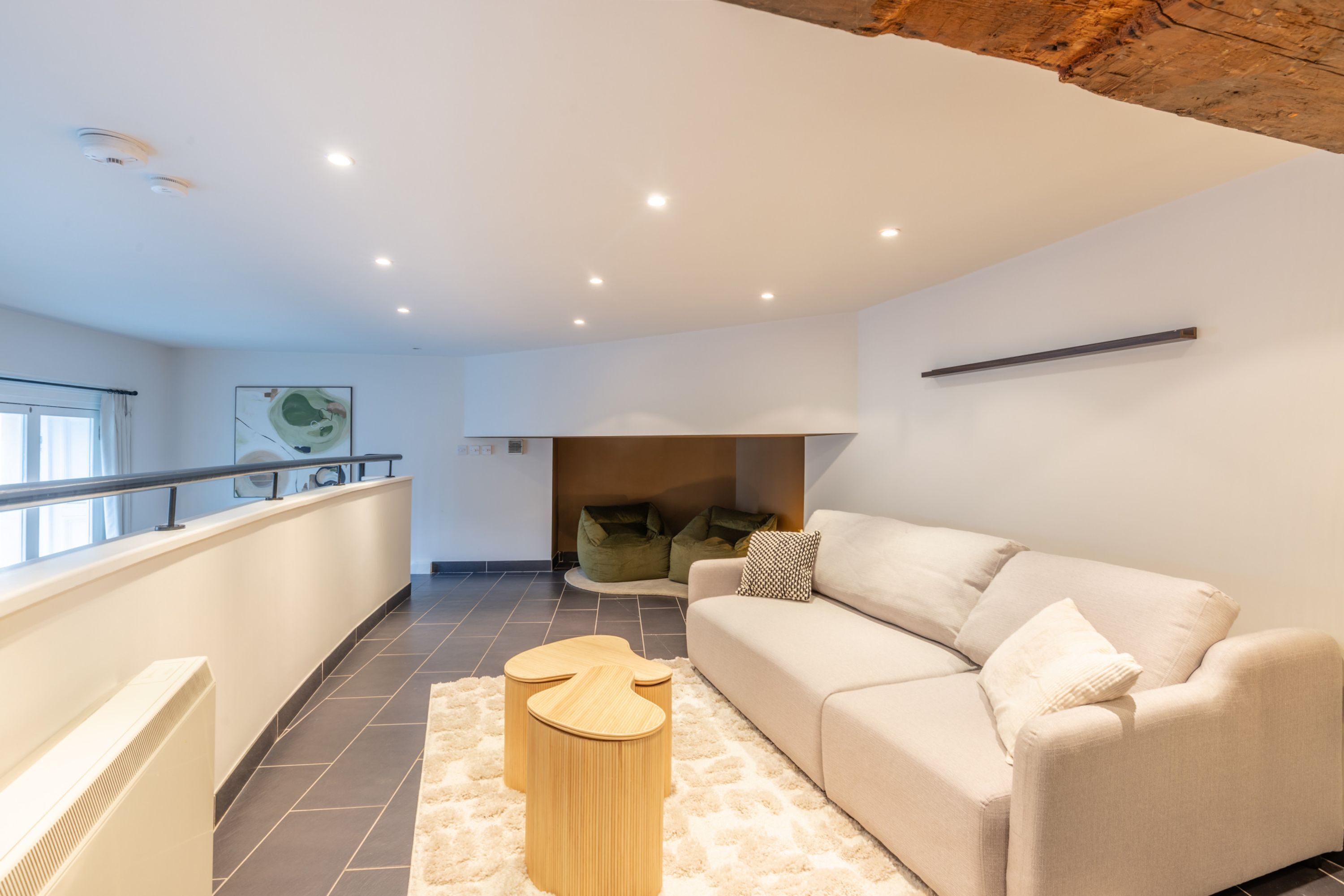 A modern living room with a beige sofa, a wooden coffee table, and a white shag rug.