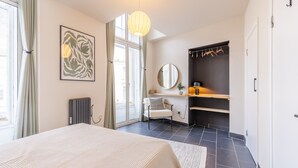 Ein modernes Schlafzimmer mit einem großen Bett, einem Schreibtisch mit Stuhl, einem Heizkörper und einem Fenster mit Vorhängen.