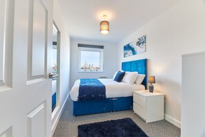 A bedroom with a bed, bedside table, lamp, and artwork on the wall. - Mindrum in North Shields (North Shields)
