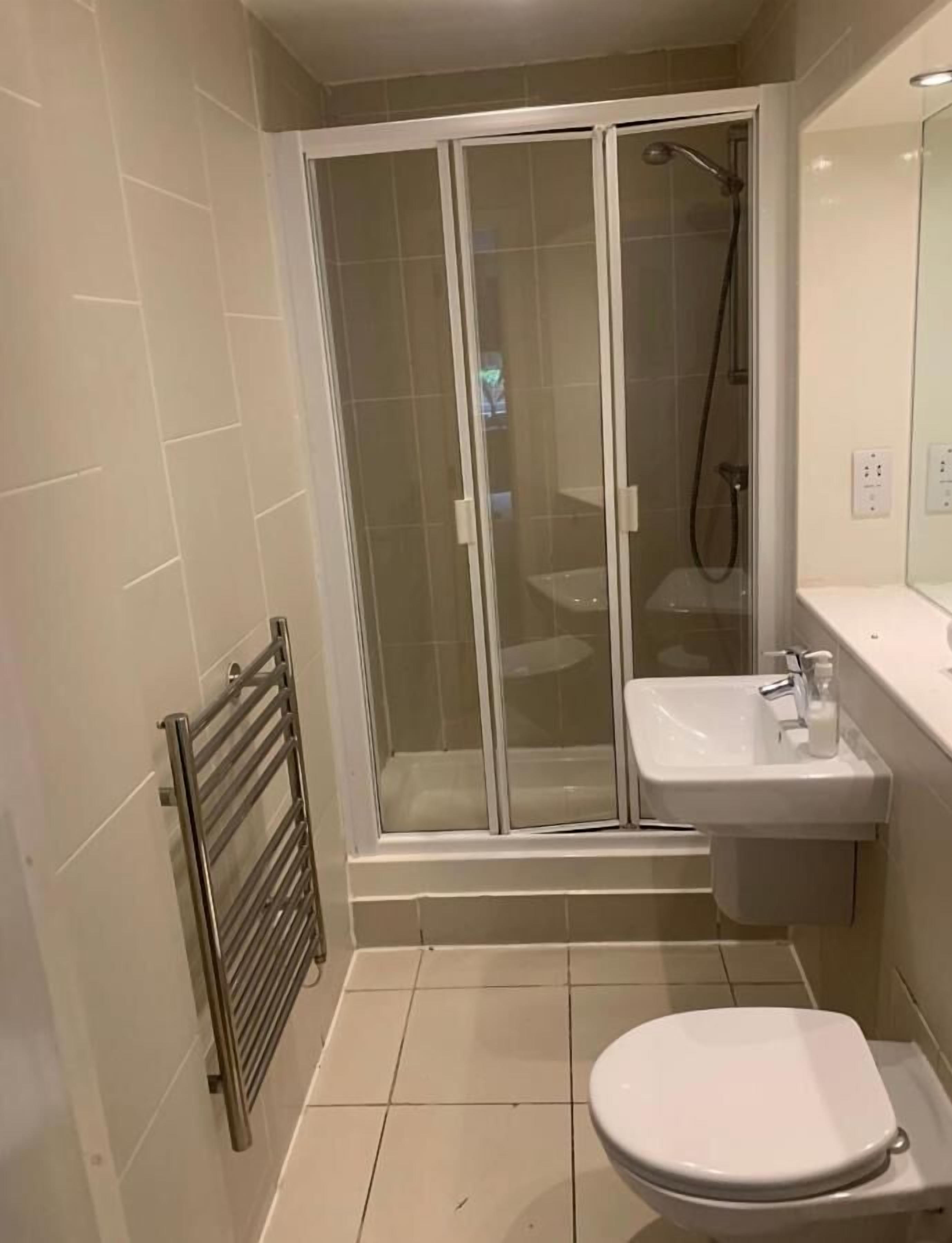 A modern bathroom with a glass-enclosed shower, a sink, and a toilet.