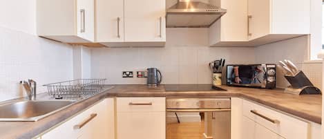 A modern kitchen with white cabinets, stainless steel appliances, and a built-in oven.