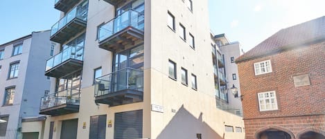 A multi-story building with a modern design, featuring balconies, large windows, and a brick facade.