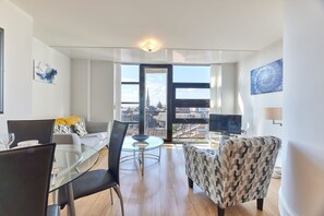 Una sala de estar moderna con una mesa de vidrio, un sofá y un sillón estampado.