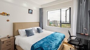Ein modernes Hotelzimmer mit einem großen Bett, einem Schreibtisch und Blick auf die Stadt.