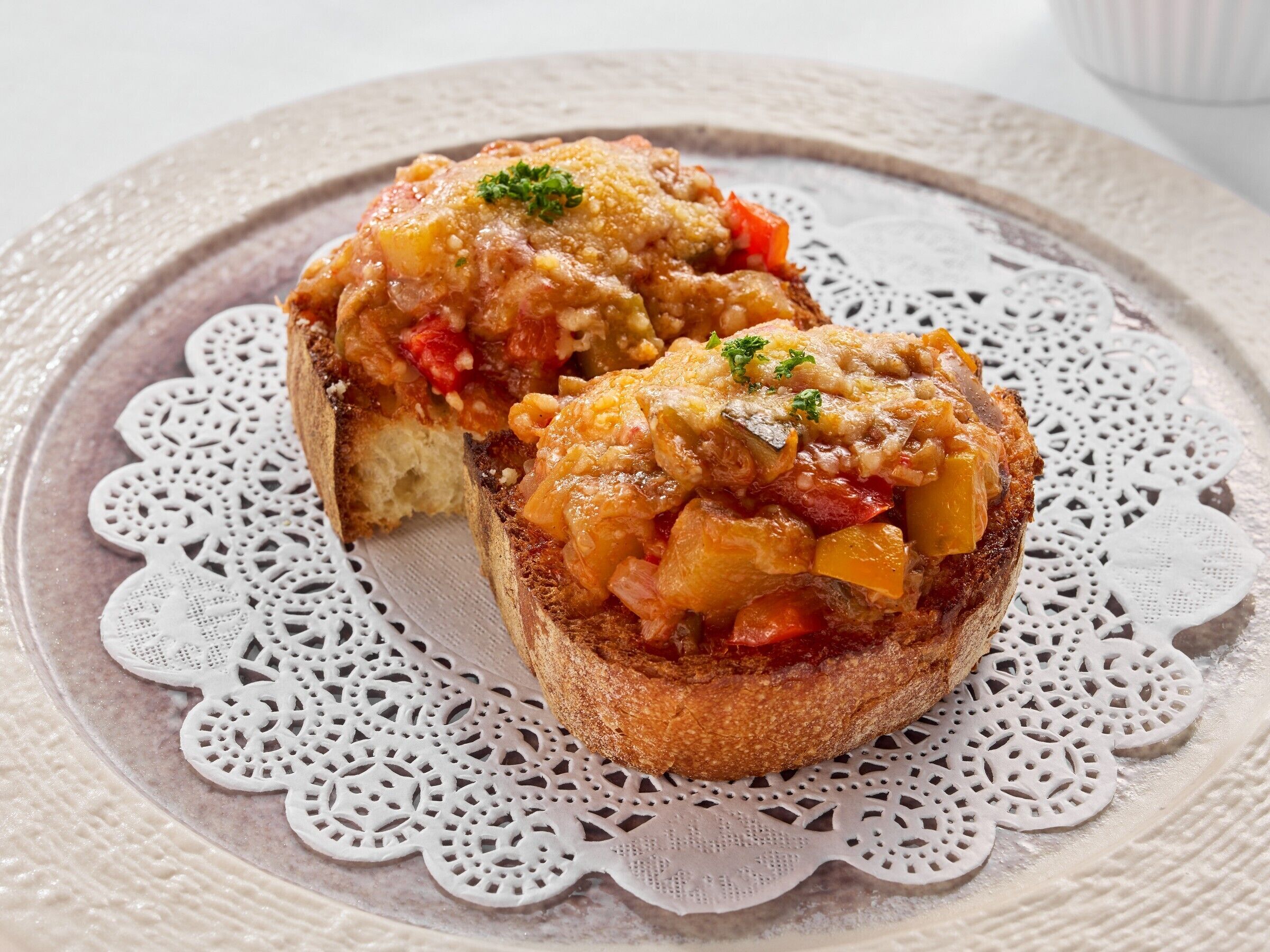 Two slices of toast topped with a savory mixture, placed on a lace doily.