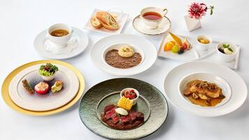 A variety of dishes including a salad, soup, and meat, arranged on different plates and bowls.