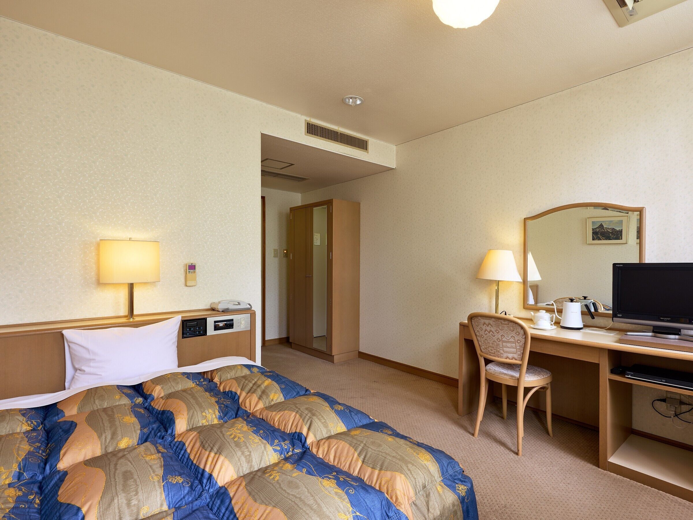 Habitación de hotel con cama, escritorio, silla y televisor.