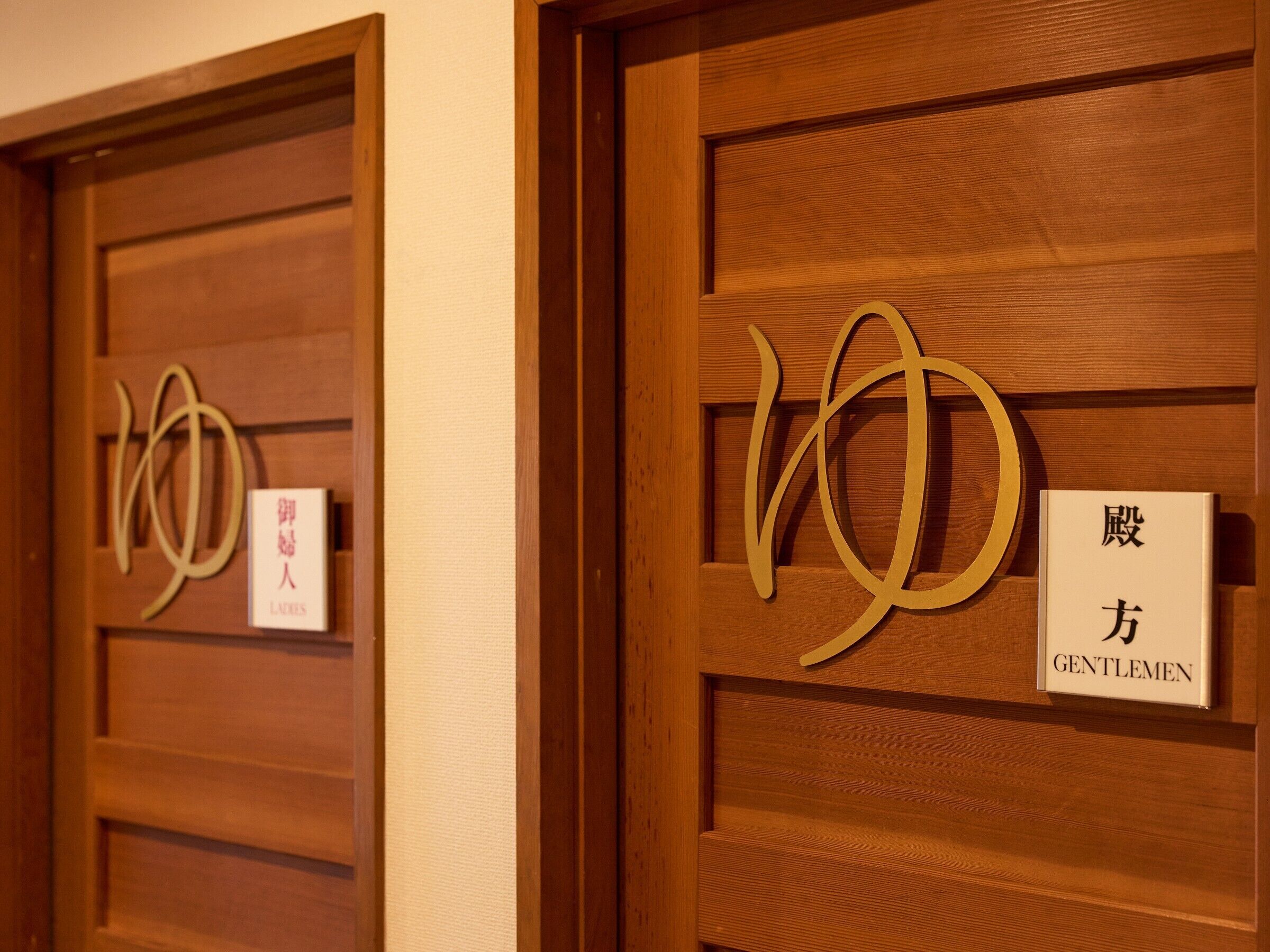 Two wooden doors with signs indicating ladies and gentlemen sections.
