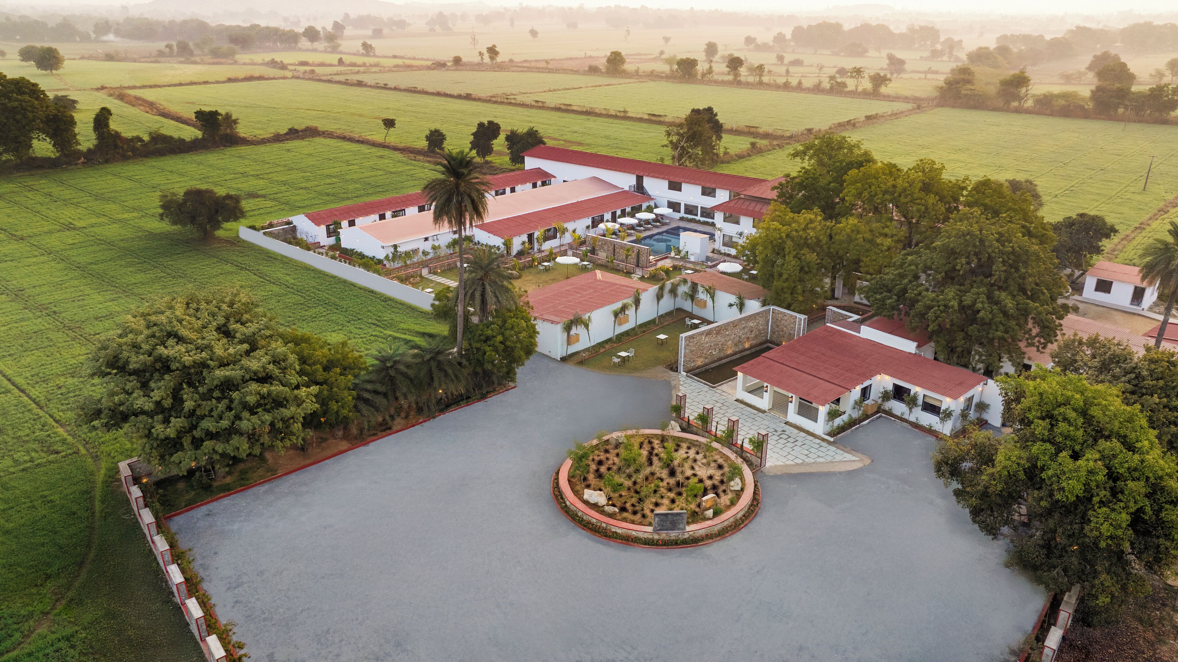 An aerial view of a large estate with multiple buildings, a central courtyard, and surrounding green fields.
