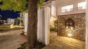 A modern building with a stone wall and a Buddha statue. - Ratan Villas Jawai (Sumerpur)