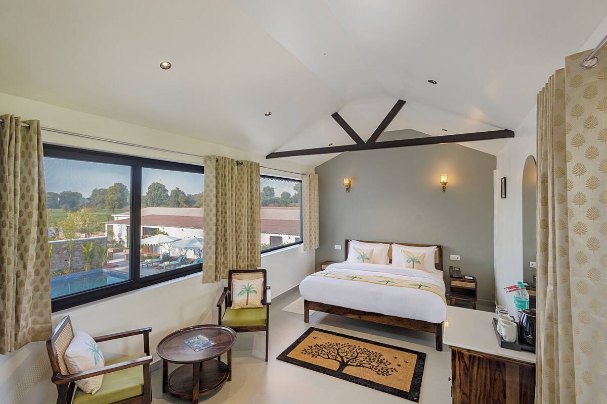 Habitación de hotel con una cama grande, un escritorio, una silla, una mesita y vistas al exterior.