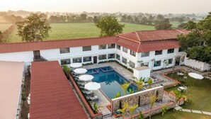A modern hotel with a swimming pool, outdoor seating, and a view of the surrounding countryside. - Ratan Villas Jawai (Sumerpur)