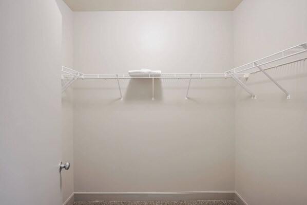 Un petit dressing vide, équipé d’une étagère métallique et d’une porte.