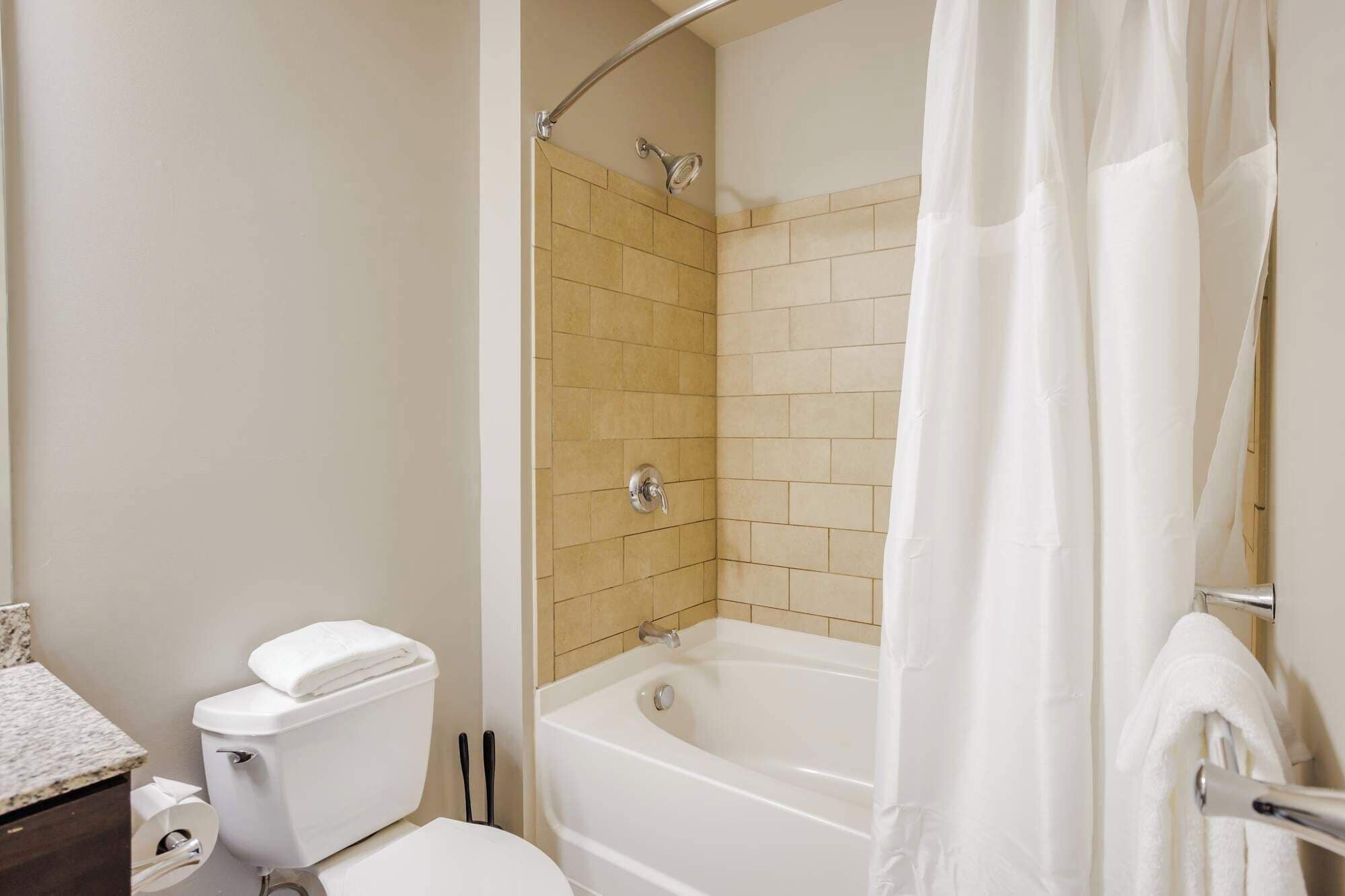 A bathroom with a toilet, a bathtub, and a shower.