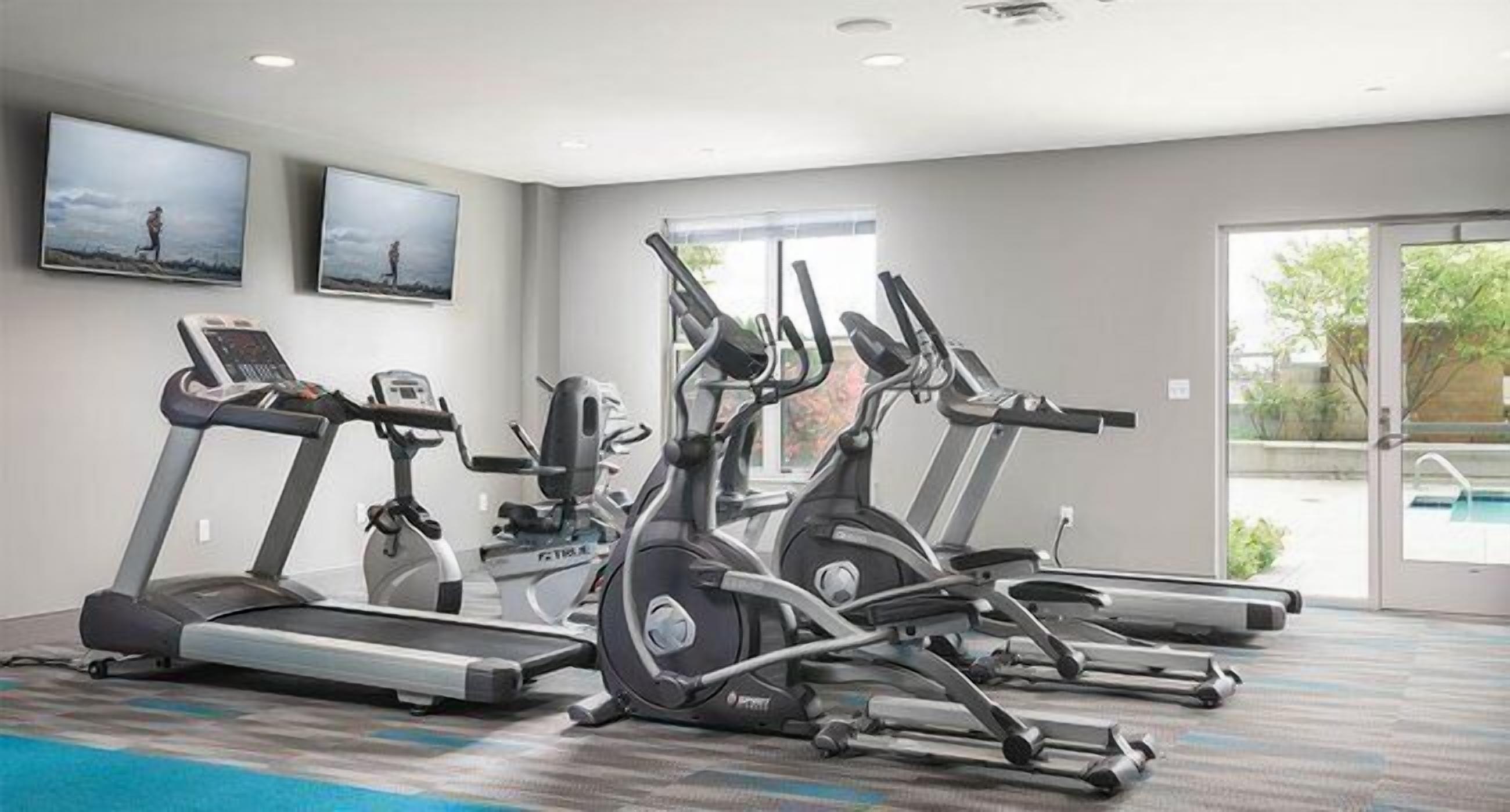 A gym with treadmills, ellipticals, and a stationary bike.