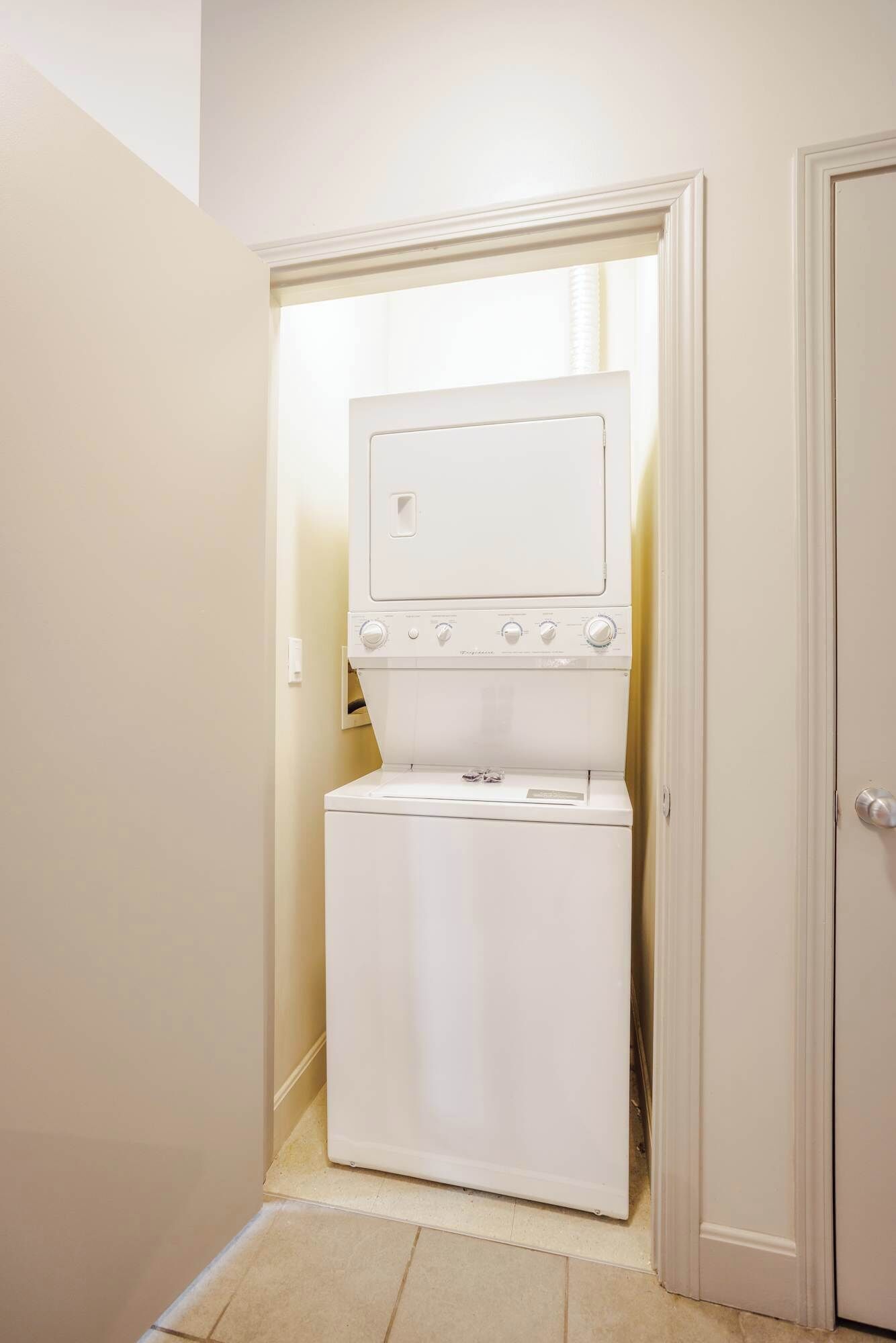 A compact laundry room with a washer and dryer, a small window, and a door.