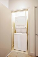 A compact laundry room with a washer and dryer, a small window, and a door.