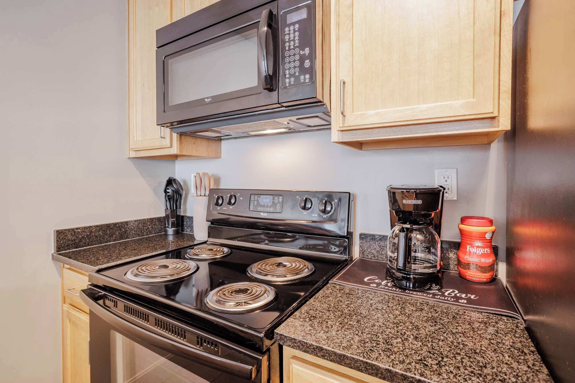 A kitchen with a stove, microwave, coffee maker, and a coffee pod.