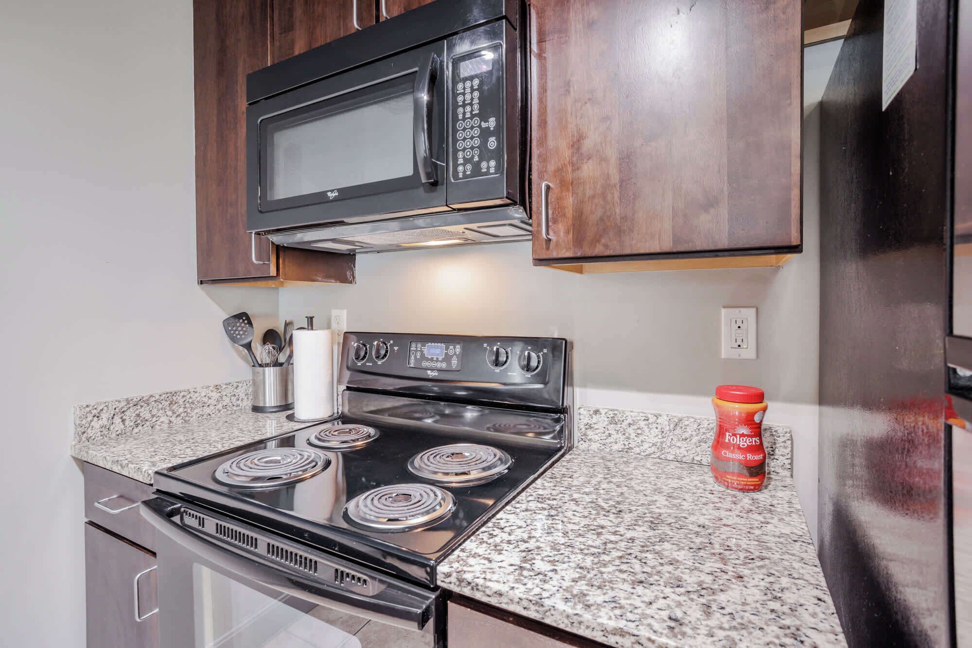A kitchen with a stove, microwave, and wooden cabinets.