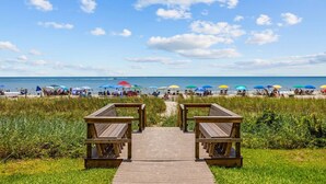 A wooden boardwalk leading to beach umbrellas and beachgoers. - *Fall into Savings-20% Off New Bookings thru 2026* (Myrtle Beach)