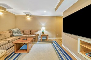 Lower Level Media Room - Large wall-mounted TV with sectional seating, teal accent lamps, and cozy lounge setting.