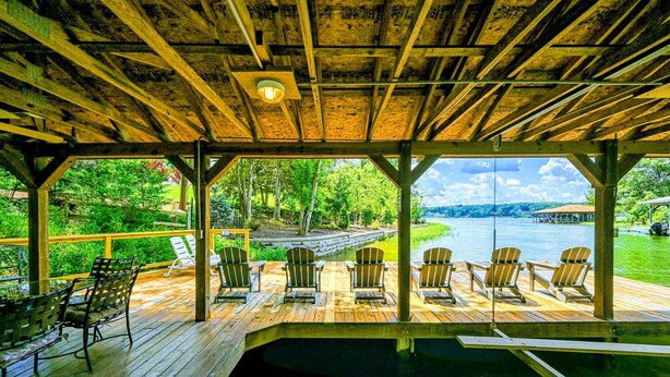 A wooden deck with a pool, chairs, and a view of a lake.