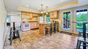 A kitchen with a central island, wooden cabinets, a microwave, and a refrigerator.