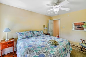 Bedroom 2 - King bed with sea-themed blue bedding, ceiling fan, and harbor painting on the wall.