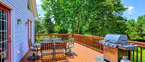 Deck - Upper-level wood deck with a round dining table, chairs, and stainless steel gas grill under the tree canopy.
