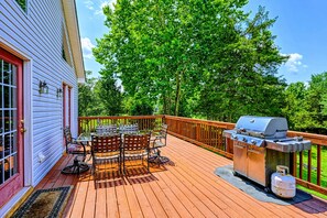 Deck - Upper-level wood deck with a round dining table, chairs, and stainless steel gas grill under the tree canopy.