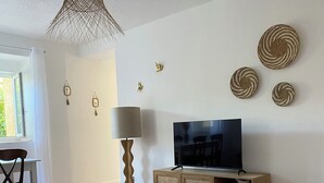 Sala de estar con televisor, aparador de madera y decoración en la pared.
