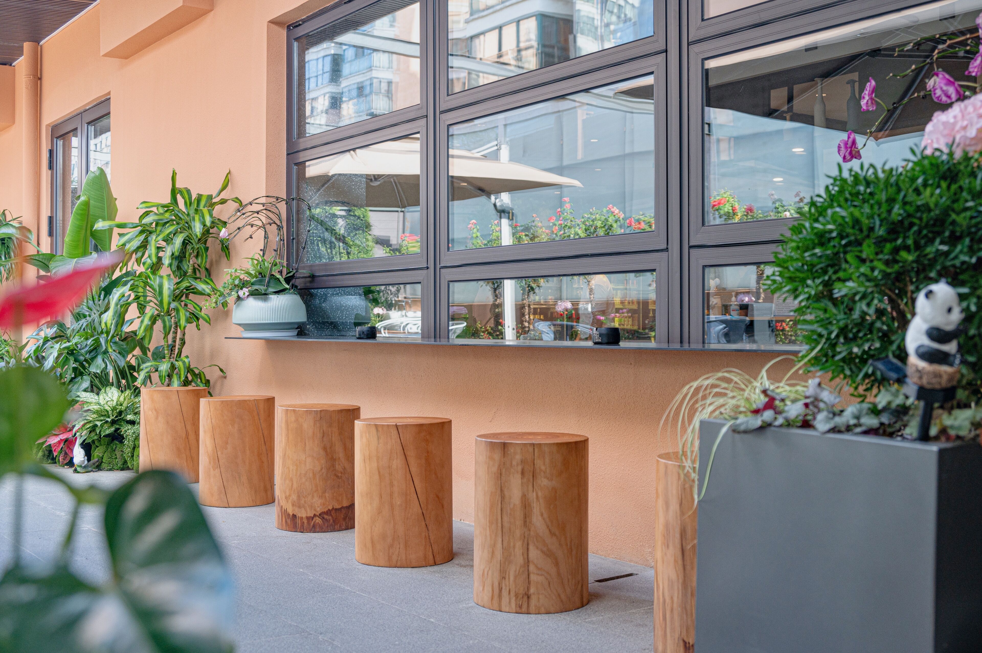 Un espace extérieur moderne aménagé avec des tabourets en bois et des plantes en pot.